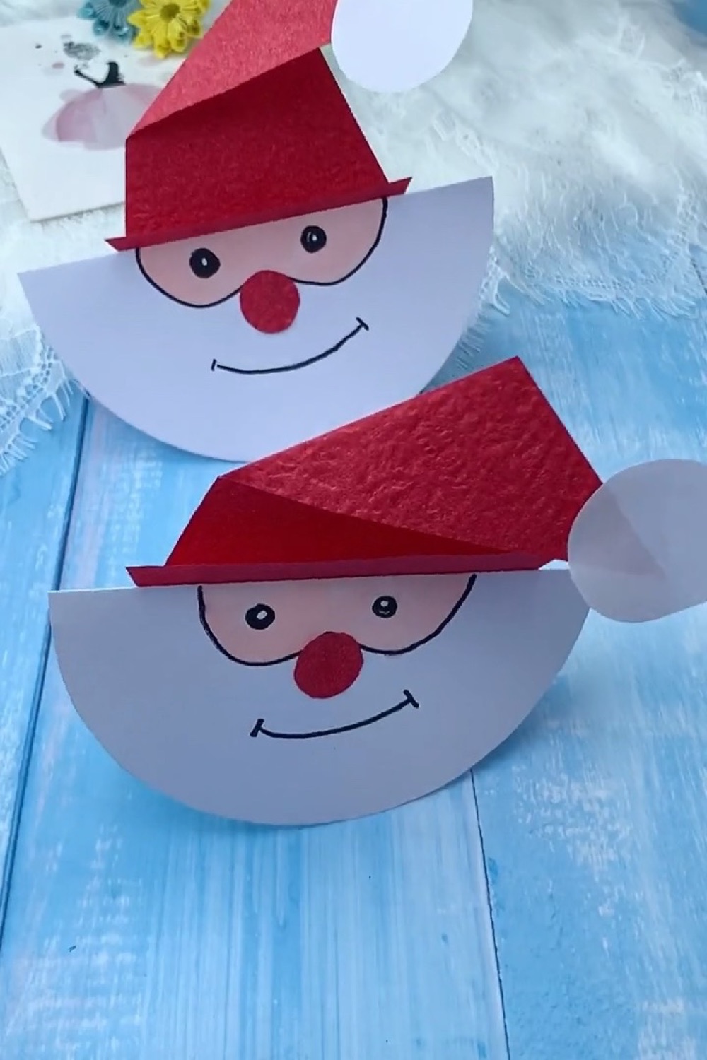 Two finished rocking paper Santas standing and rocking on wooden tabletop