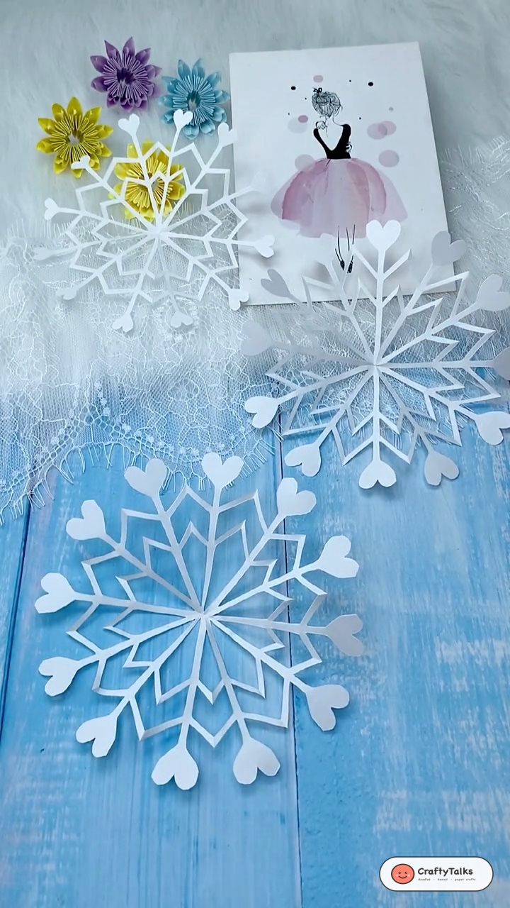 Intricate Kirigami Paper Snowflakes with Heart Shaped Points on Festive Table