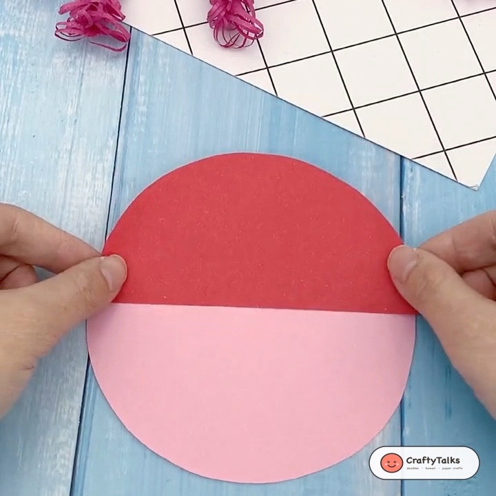 Step 1: Affixing red cardstock semicircle over top half of pink circular base to form Santa hat crown