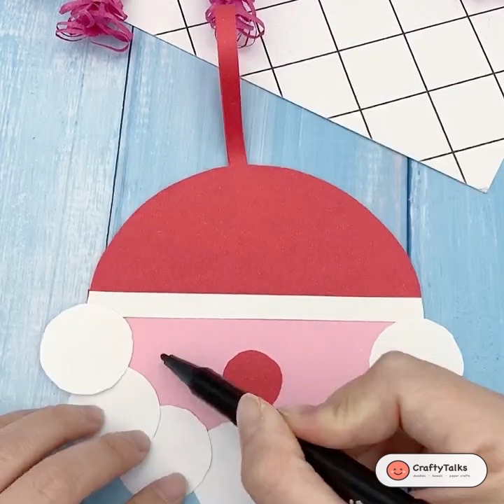 Step 5: Gluing red circle button nose, attaching top ribbon hanging loop, and creasing curved smiling eyes