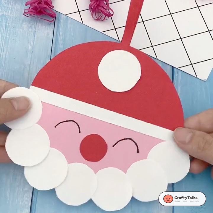 Step 6: Gluing crisp white circular pompom to crown of red hat to complete Santa bauble