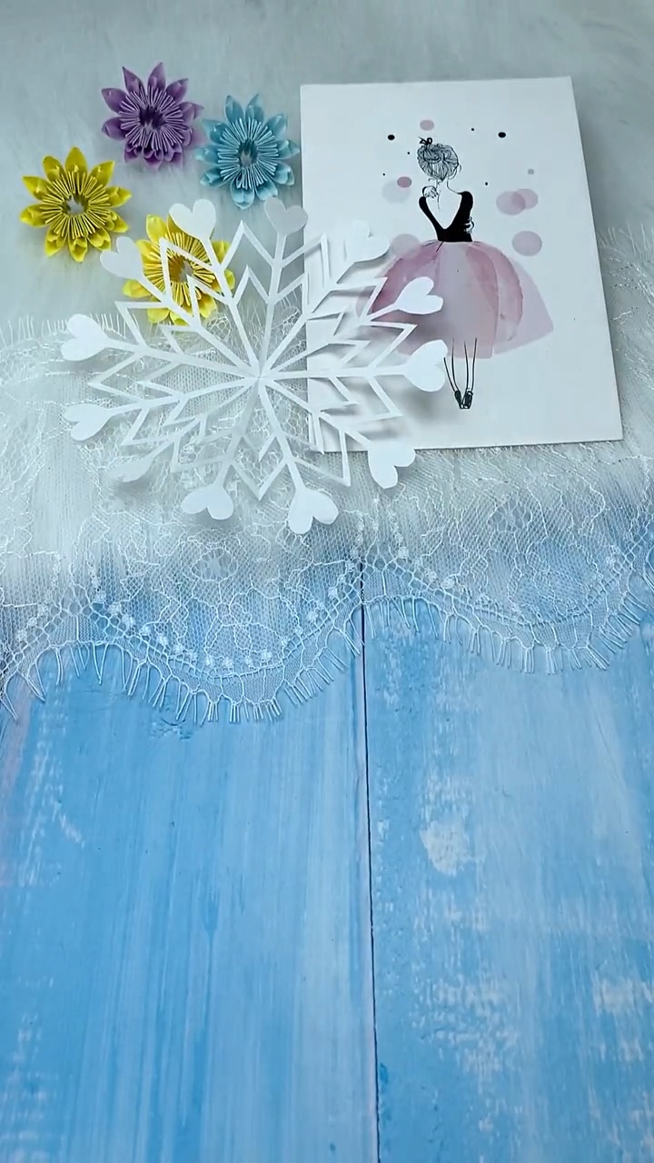 Trio of Lacy Heart Tipped Paper Snowflakes Displayed on Blue Wooden Surface